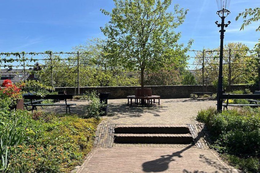 A garden with benches, a brick pathway, and a tree. 4