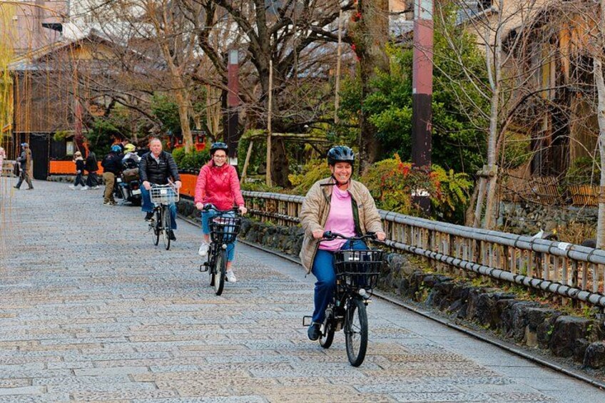 Un camino adoquinado con ciclistas, una barandilla de metal y árboles. 2