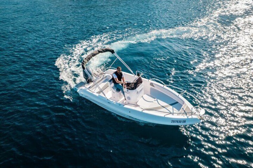 A small white motorboat on a calm sea with a person steering. 3