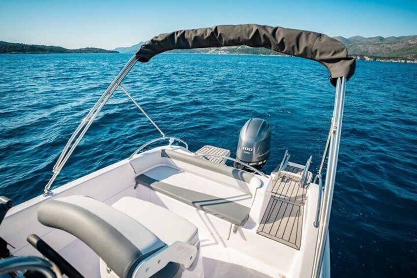 A boat with a canopy, white seating, and a motor on the back. 4