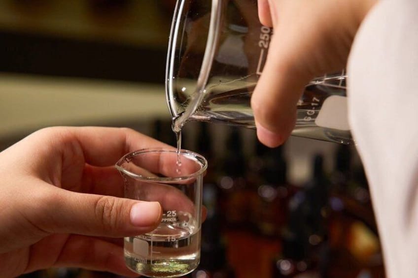 A person pouring a clear liquid from a measuring cup into a small glass. 5