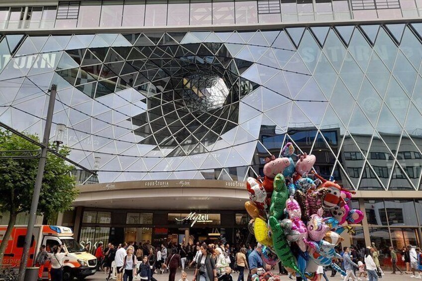 A modern building with a glass facade and a large, colorful sculpture of animals in front. 2