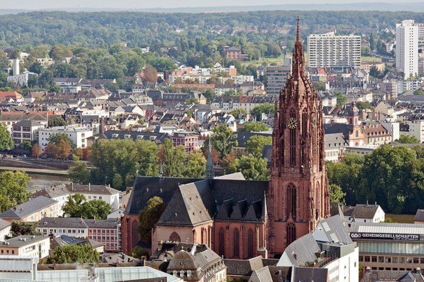 A cityscape with a prominent red church tower, a modern building labeled 'GEMEINSPELLEINNEN,' and a dense urban area with various buildings and greenery. 3