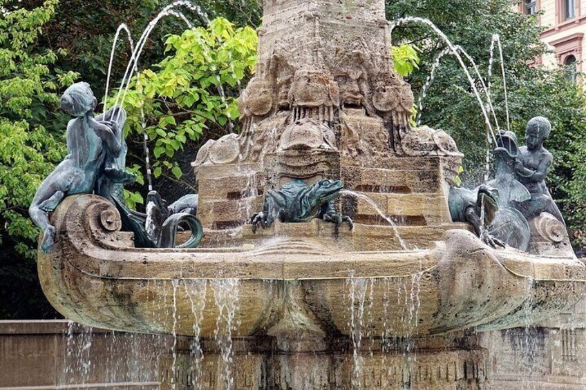 A stone fountain with multiple water jets and statues of children and animals. 5