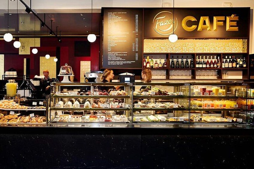 A café interior with a menu board, pastries display, and a wine selection. 3