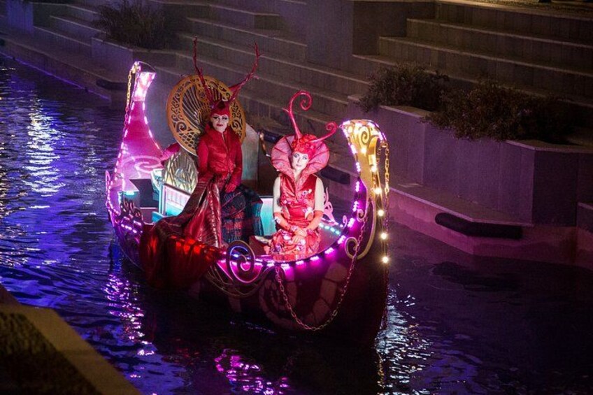 A boat with illuminated decorations and figures on a water body at night. 4