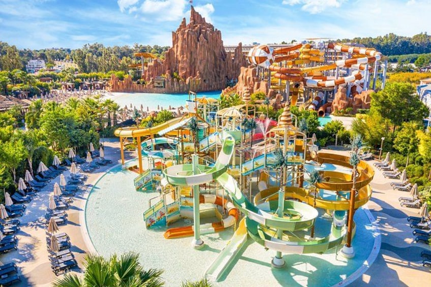 A water park with multiple slides and pools, surrounded by beach chairs and umbrellas. 1