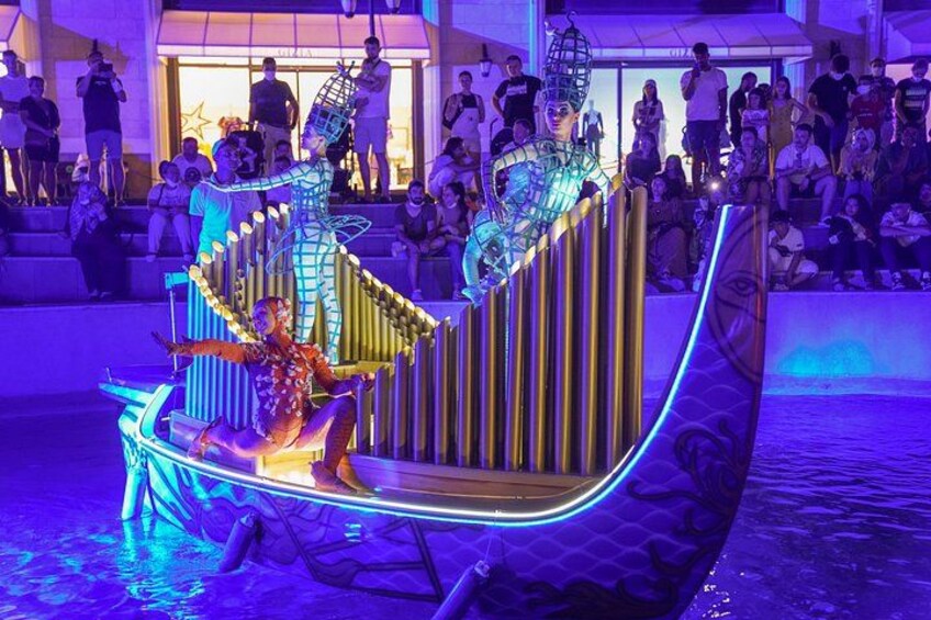 A performer on a brightly lit, illuminated stage with a crowd watching. 5