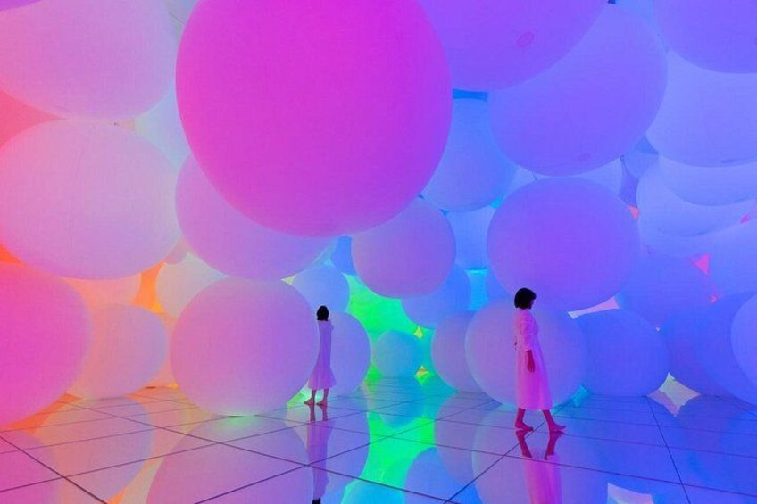 A person walking through a space with large, colorful spherical structures. 1