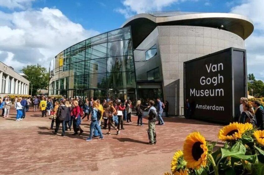 The Van Gogh Museum in Amsterdam with a modern glass building and a crowd of visitors. 1