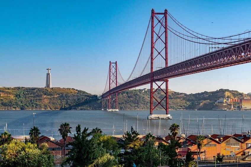 A red suspension bridge over a body of water, with a hill and a lighthouse in the background. 4
