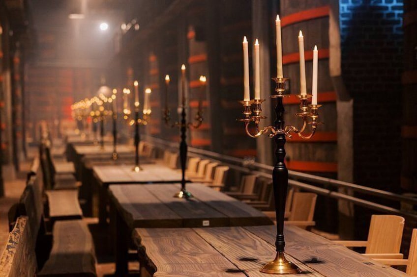 A long table with candles and benches in a dimly lit room. 3