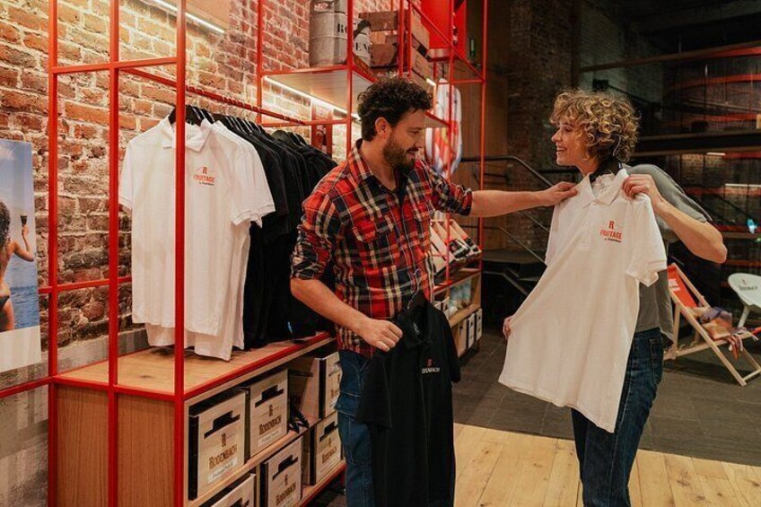 A clothing store with racks of shirts and a person trying on a shirt. 5