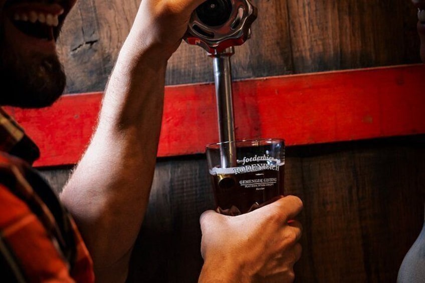 A person pouring a dark liquid from a tap into a glass. 4