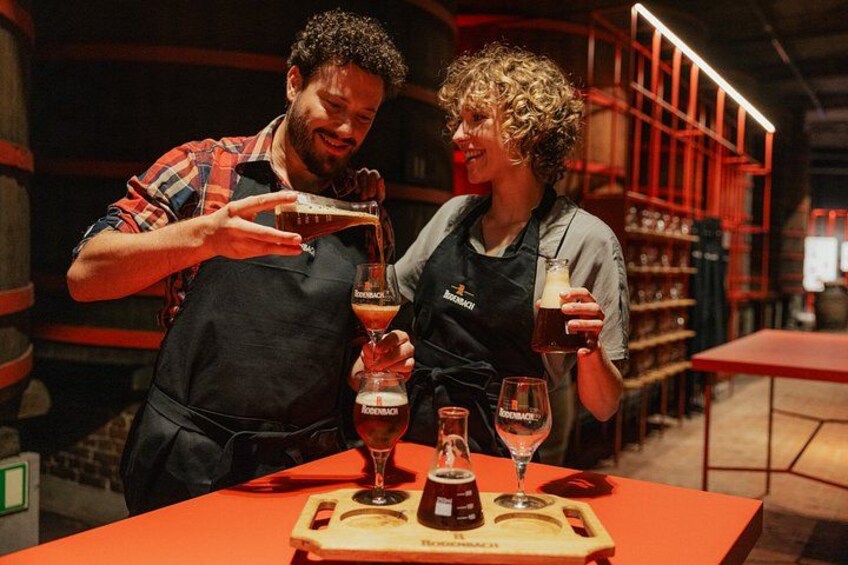 Two people tasting beverages at a bar with shelves in the background. 2