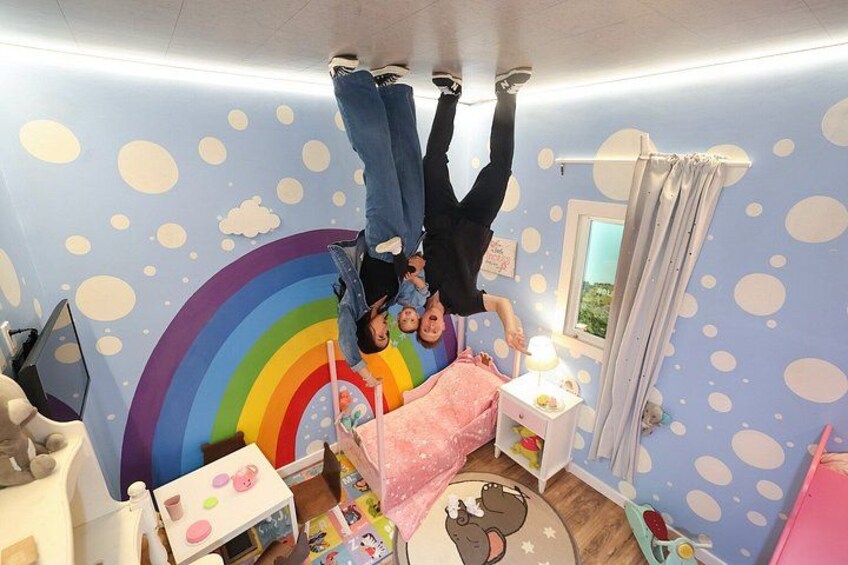 Una stanza con un murale a forma di arcobaleno, un letto, un comodino, una sedia e una finestra con tende. 4