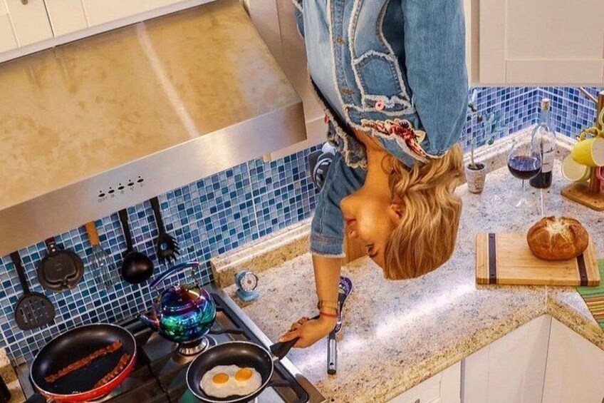 Una persona cucina uova su un fornello in una cucina con piastrelle blu e una padella rossa. 5