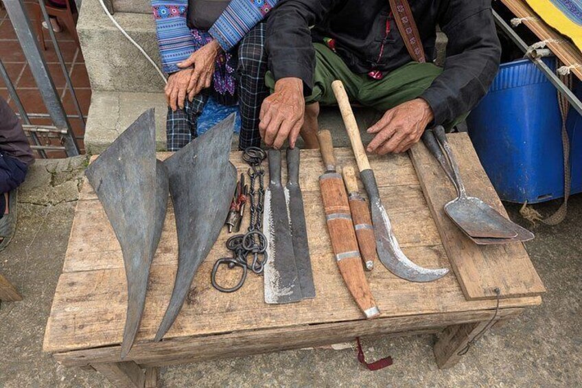 A wooden table with various tools including a shovel, a pickaxe, and a pair of trowels. 5