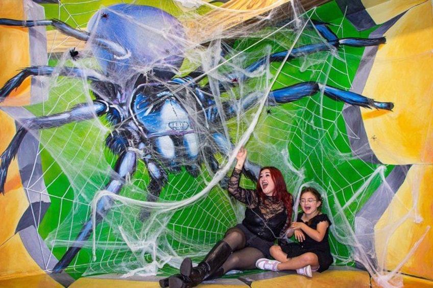 Une grande structure en forme de toile d’araignée, avec une araignée robotique au centre, entourée de formes géométriques colorées. 5