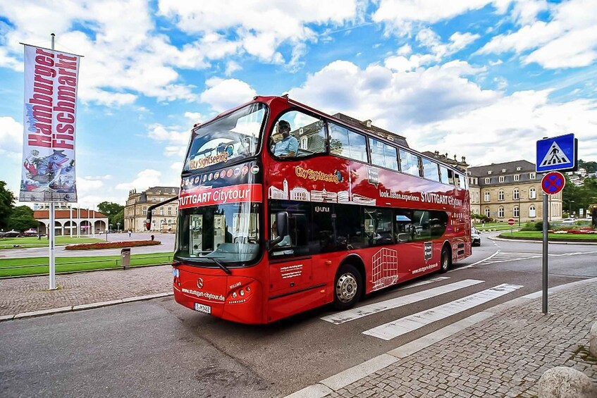A red double-decker bus with 'City Sightseeing Hamburg' on the side, driving on a city street. 1