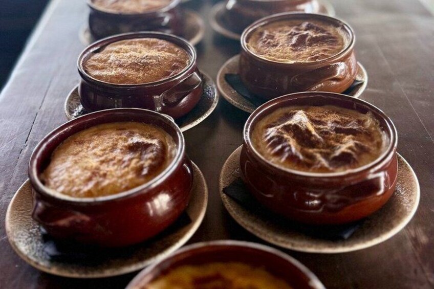A row of ramekins with a dessert, possibly crème brûlée, on a wooden table. 4