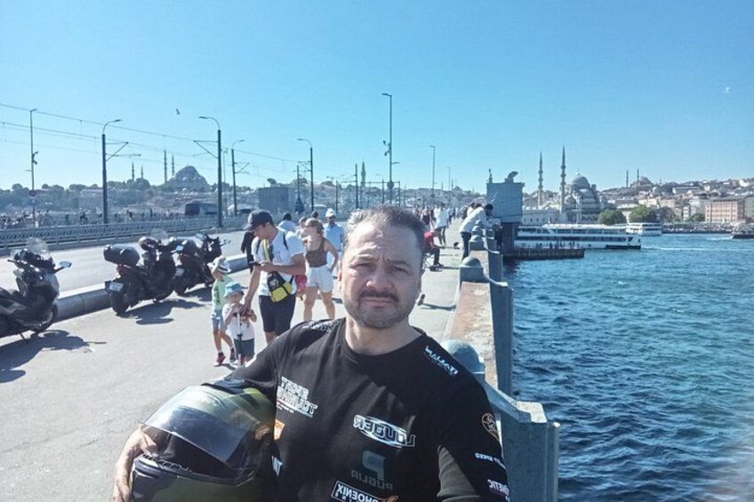 A man standing on a waterfront promenade with a cityscape in the background. 3