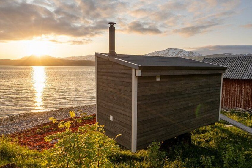 A wooden shed by a lake with mountains in the background. 3