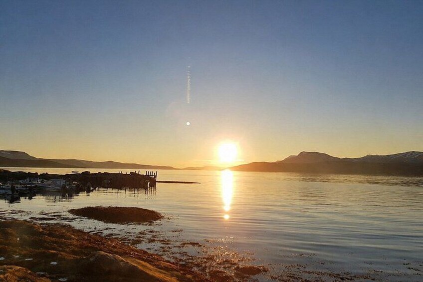 A sunset over a calm lake with a pier and distant mountains. 5