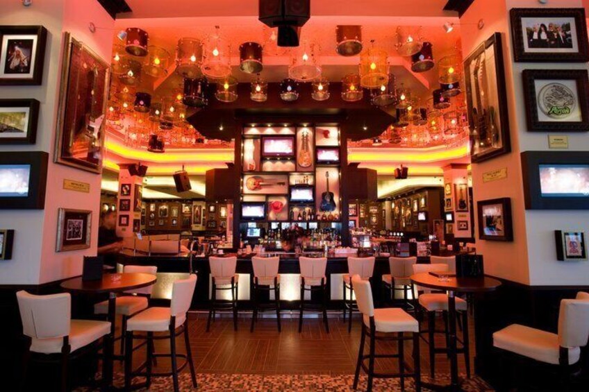 A bar with multiple seating areas, a bar counter, and various framed pictures on the walls. 2