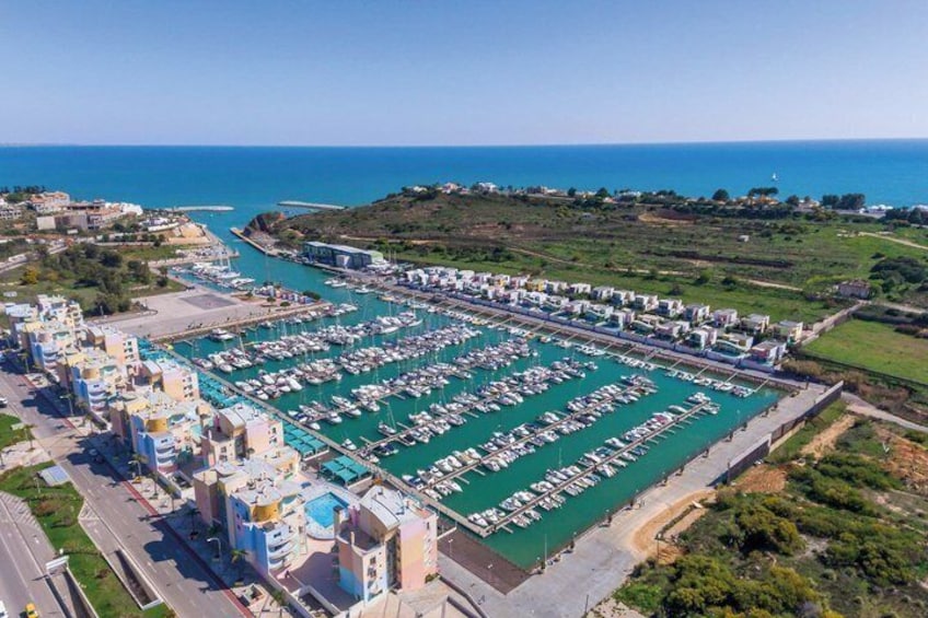 An aerial view of a marina with boats docked, surrounded by buildings and a coastline. 3