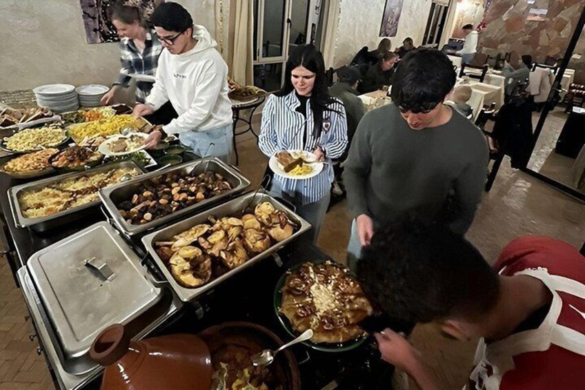 A buffet with various food items and people serving and eating. 5