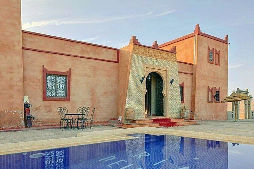 A building with a pool, a table and chairs, and a decorative archway. 3