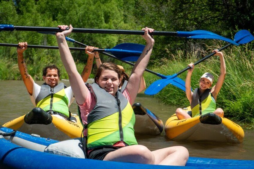 People kayaking on a river surrounded by greenery. 2