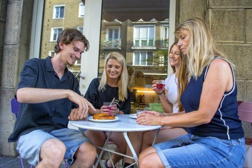 Four people sitting at an outdoor table with a plate of food and drinks. 1
