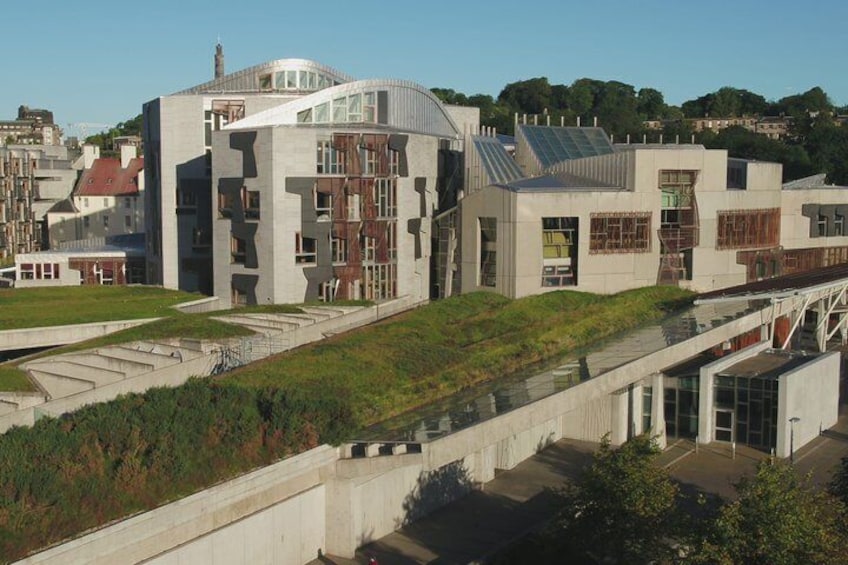 A modern building with a unique architectural design, surrounded by greenery and a clear sky. 5