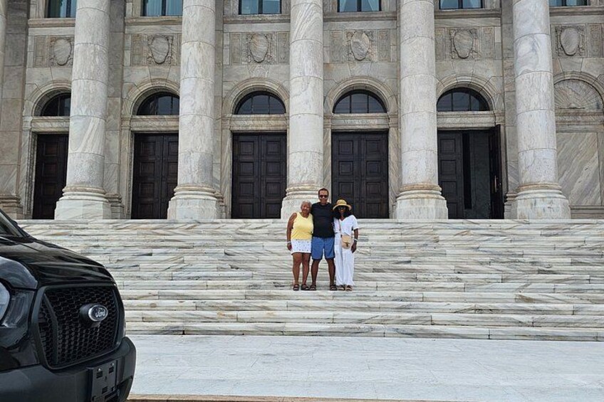 A building with large columns and a black car parked in front. 4