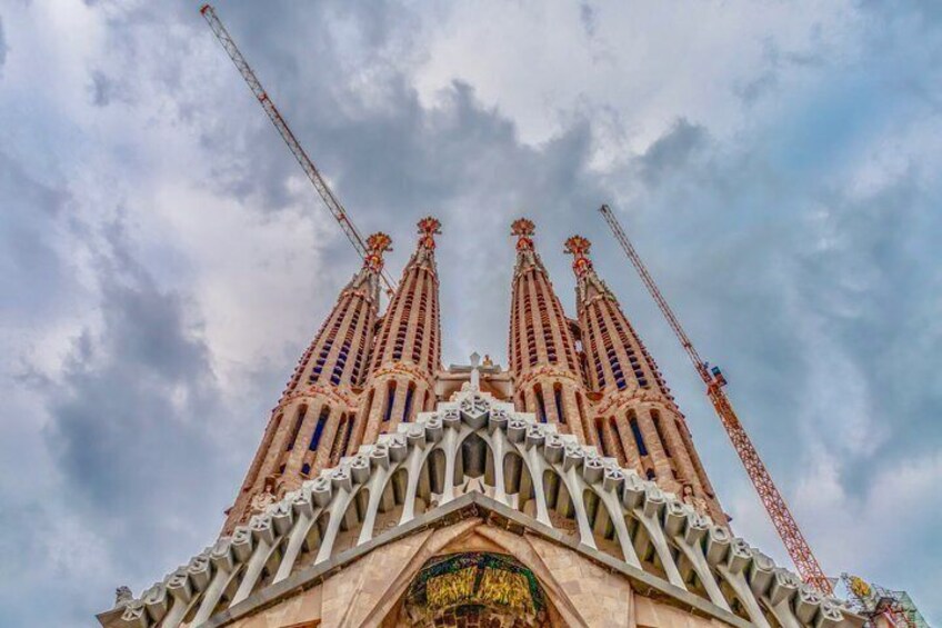 The Sagrada Familia's facade with multiple spires and construction cranes. 4