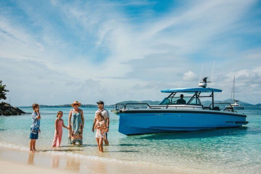 A family standing on a beach with a blue boat in the water. 1