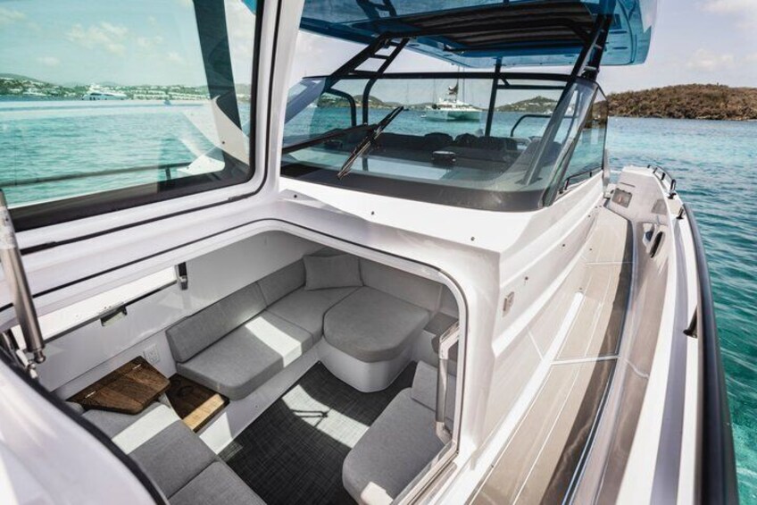 A boat's interior with a cushioned seating area and a clear view of the water outside. 4