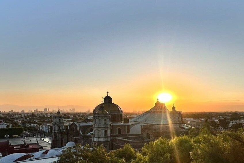 A cityscape with a prominent church and a large dome, with the sun setting in the background. 1