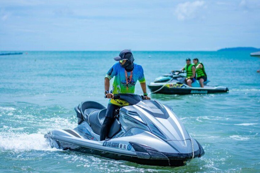 A person riding a jet ski on water with another jet ski in the background. 4