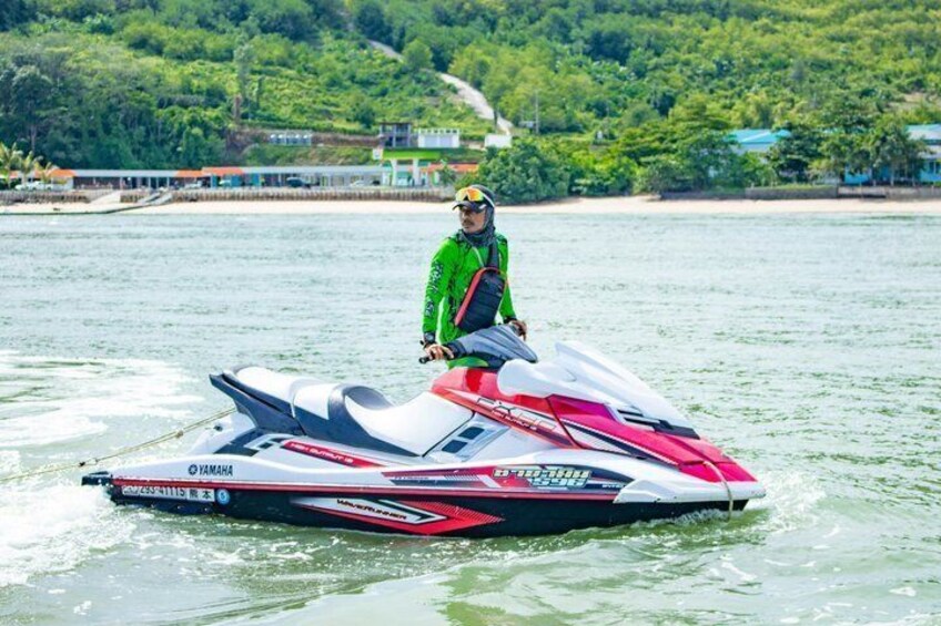 A person on a Yamaha jet ski on water with a forested shoreline in the background. 3