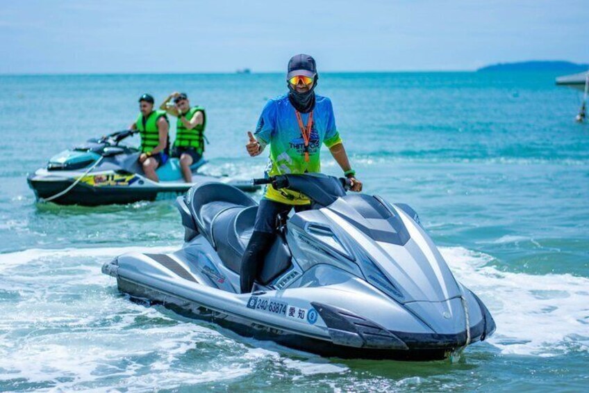 A person riding a jet ski on a body of water with another jet ski in the background. 5