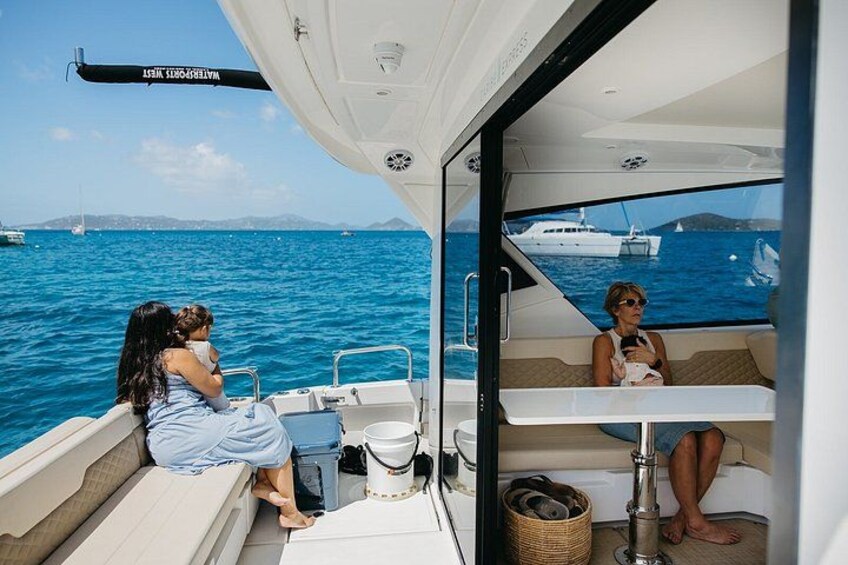 A boat with two people sitting at the bow, a clear blue sea, and distant boats in the background. 2