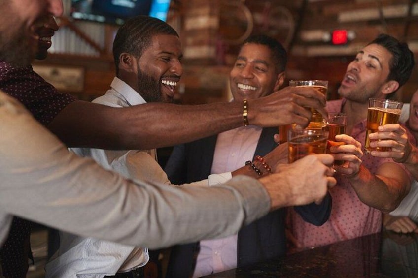 A group of people toasting with beer glasses in a bar setting. 2
