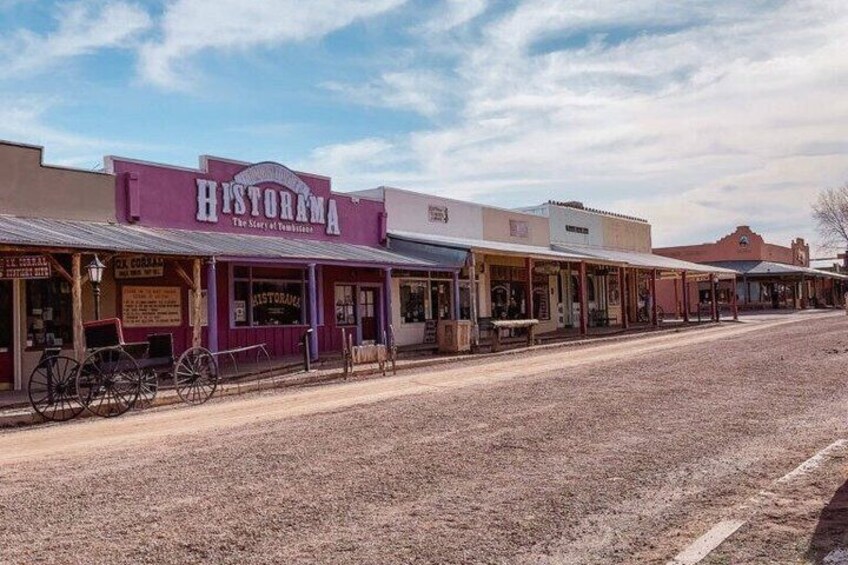 A historic street with buildings, including a prominent 'HISTORAMA' sign, and a dirt road. 3