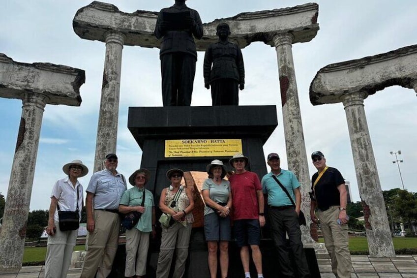 A group of people standing in front of a historical monument with columns and statues. 1