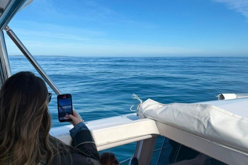 A person on a boat taking a photo of the ocean. 4