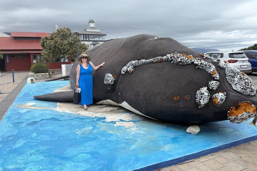 A large whale sculpture with a woman standing beside it. 2