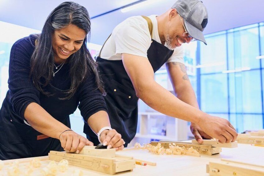 Two people working with wooden blocks and tools, likely engaged in a craft or construction activity. 3